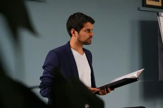 Male actor in a suit with a script in his hand.